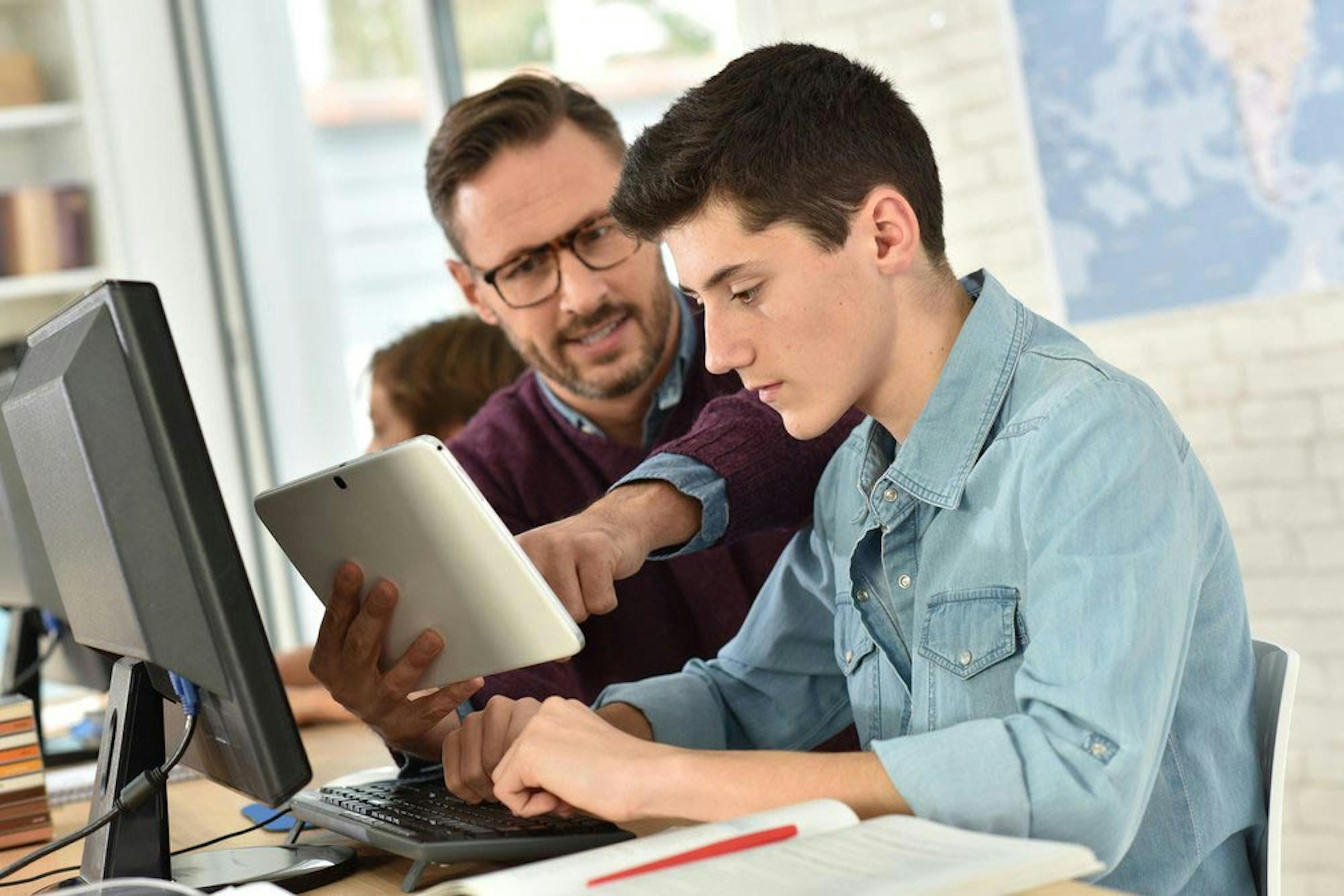 Teacher Aide helping a teenage student with technology