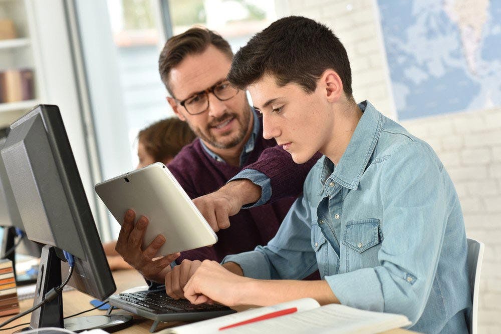 Teacher Aide helping a teenage student with technology