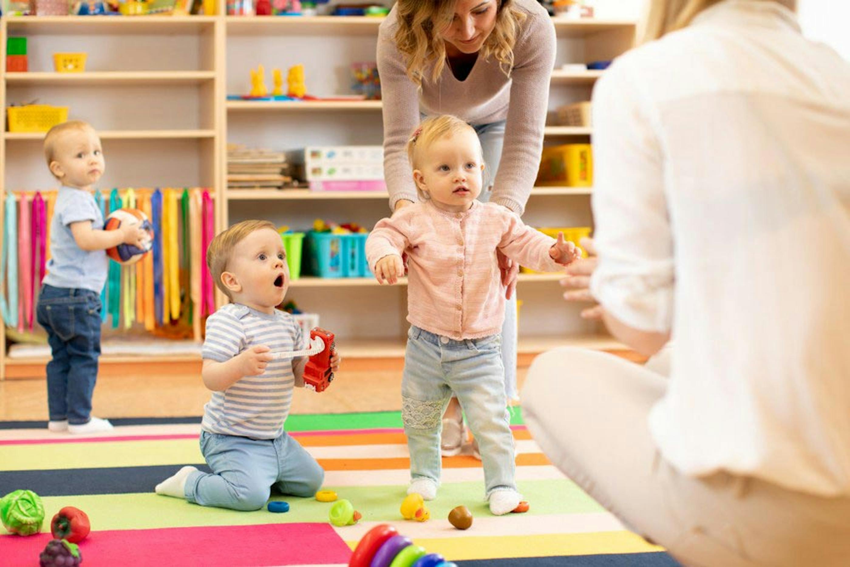 Childcare workers helping toddlers interact with each other
