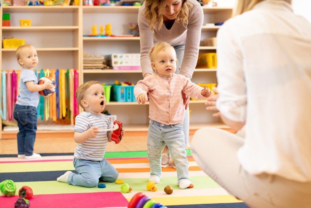 Childcare workers helping toddlers interact with each other