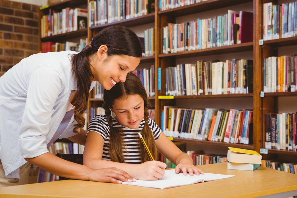 Teacher aide helping a young student with her studies