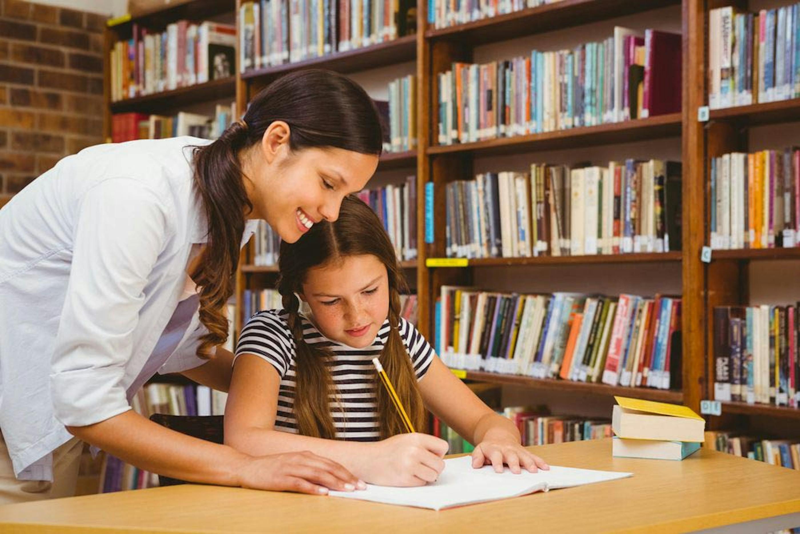 Teacher aide helping a young student with her studies