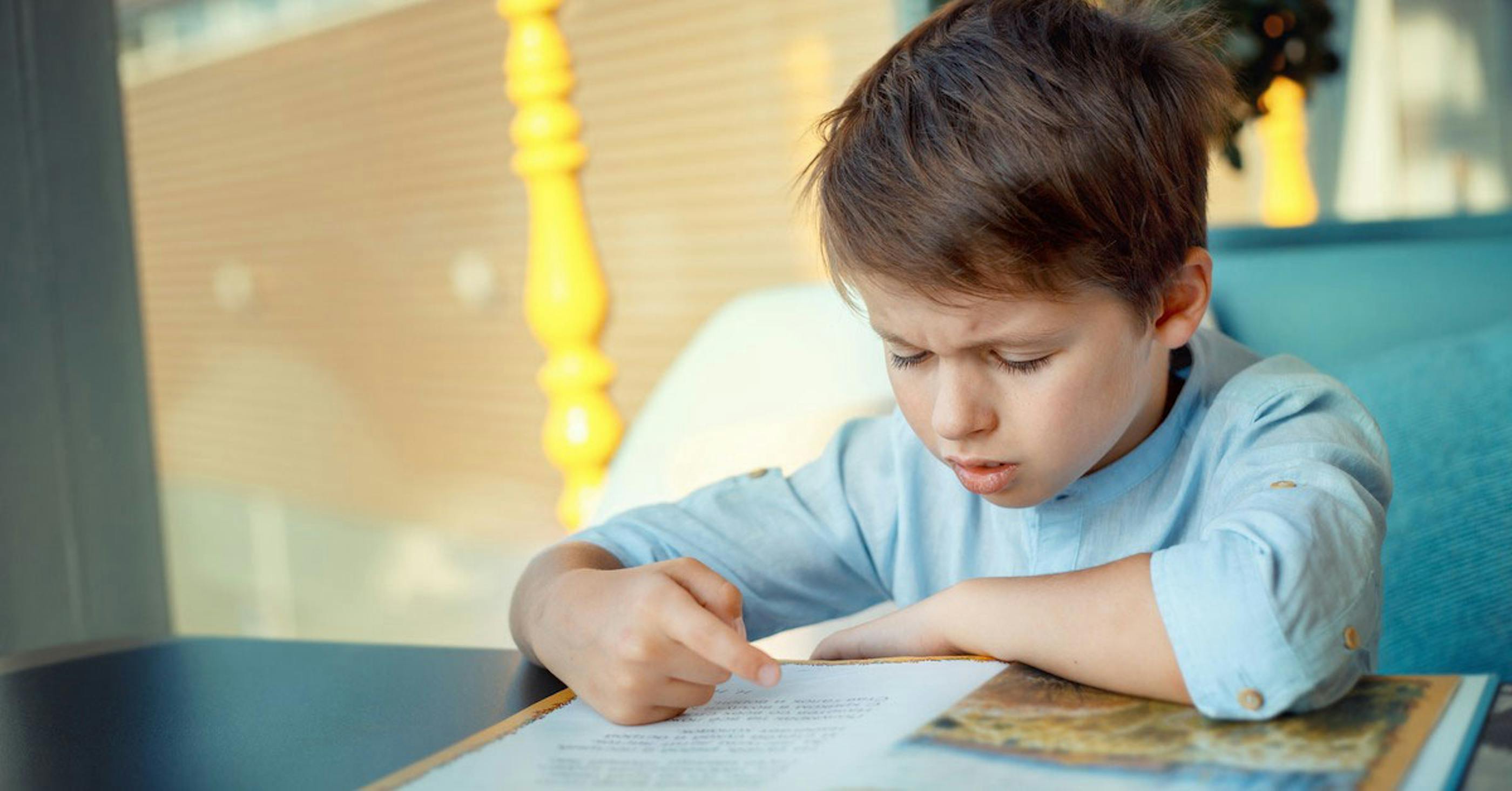 Young student with dyslexia struggling to read through informative book