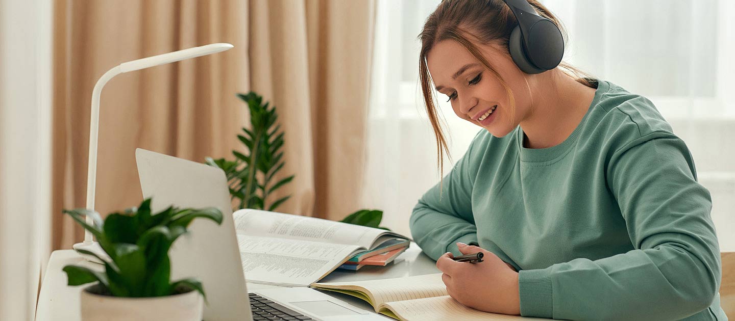 Girl using laptop and writing in notebook