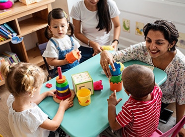 Kindergarten assistant surrounded by children