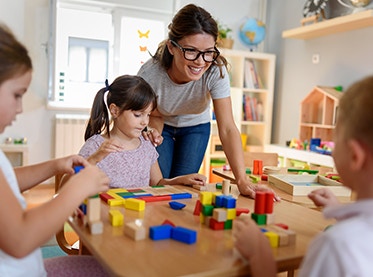 Childcare assistant surrounded by children