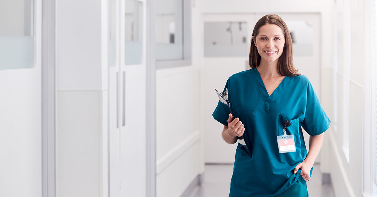 Health Worker Wearing Scrubs Standing In Hospital Corridor