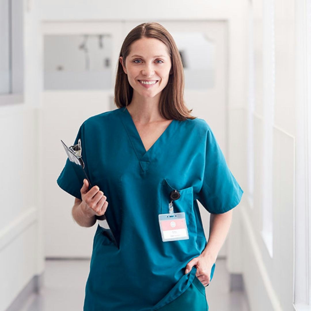 health worker wearing scrubs standing in hospital corridor