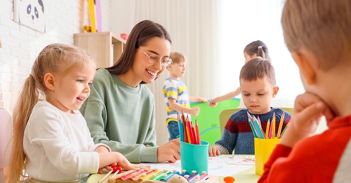 Childcare Educator working with 3 children on drawings