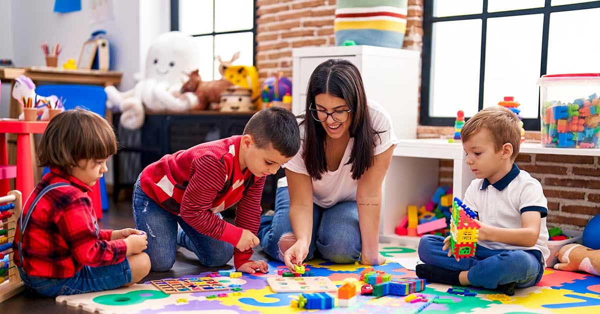 Childcare educator and children playing with building blocks