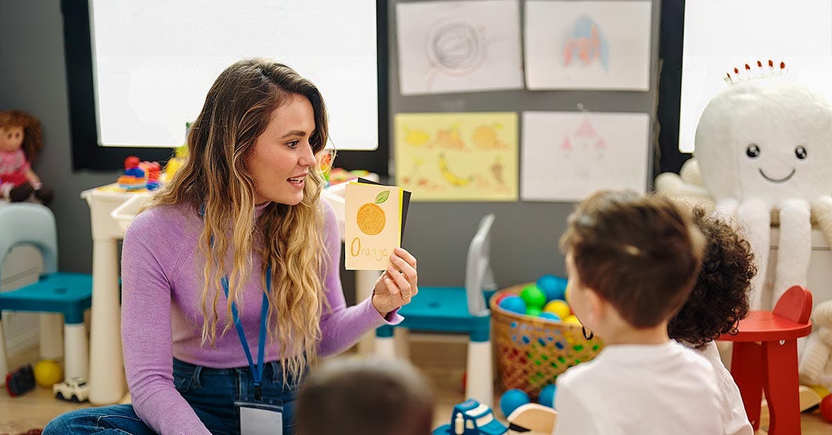 Childcare Educator showing an orange image to children