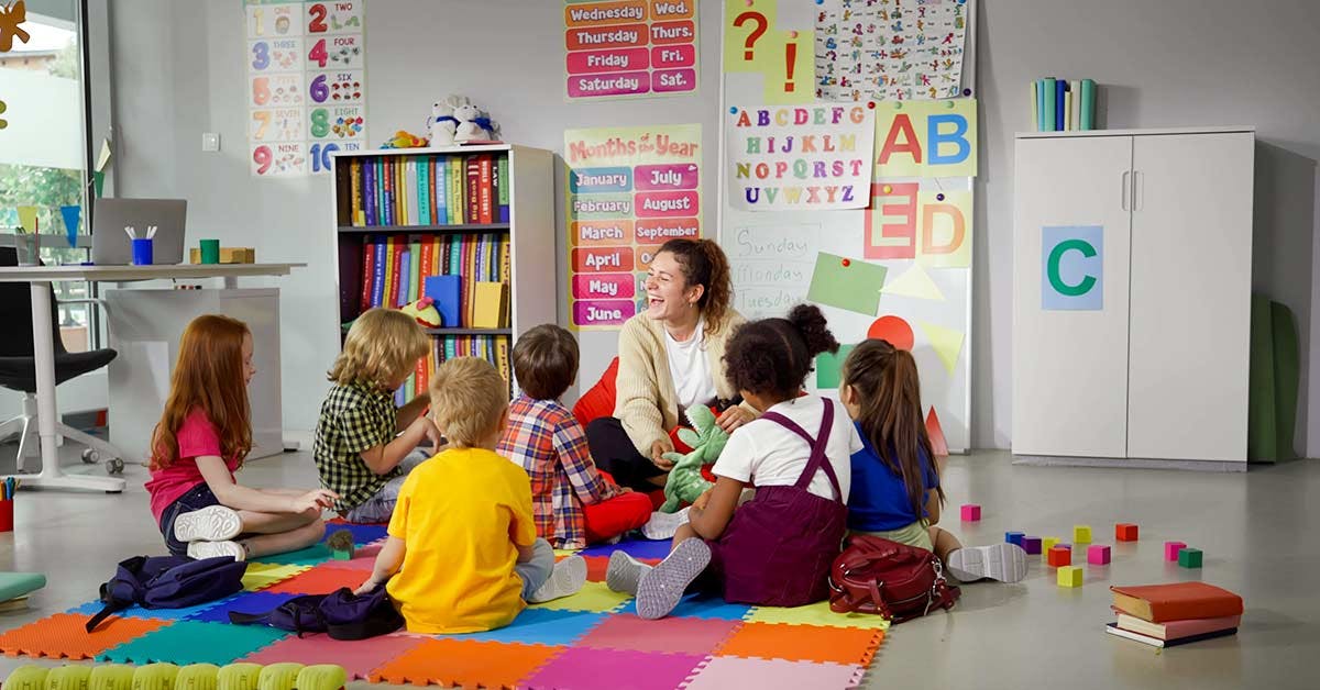 Childcare educator sitting down with her class