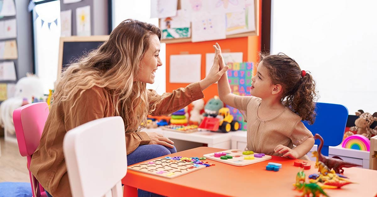Childcare educator hi five with student