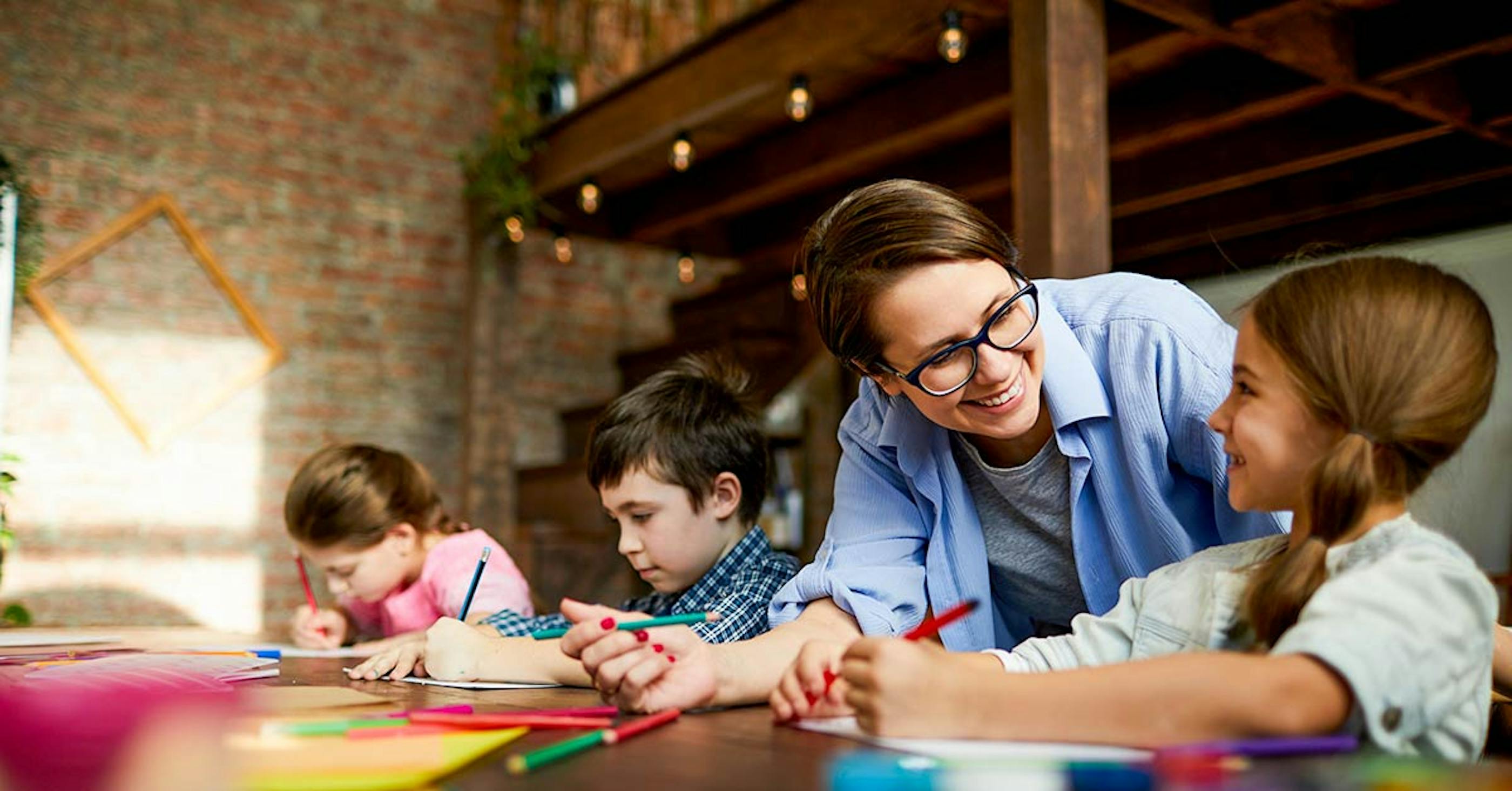 Childcare Educator working with 3 children on drawings