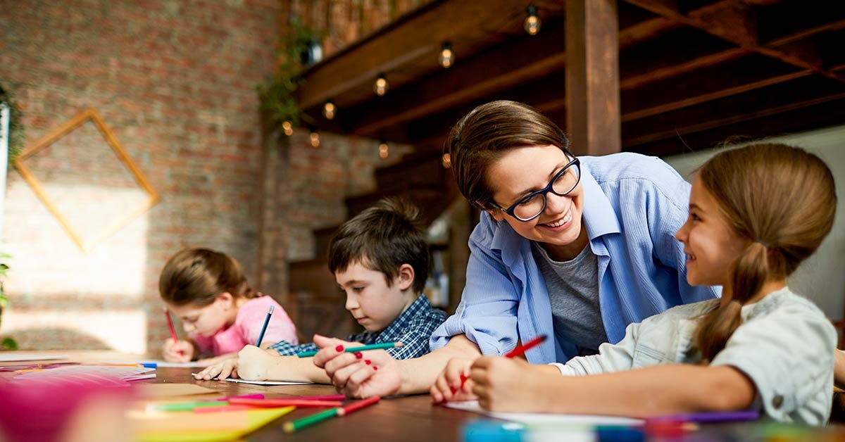 Childcare Educator working with 3 children on drawings