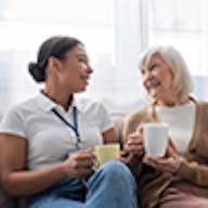 Woman serving a cup of tea to an elderly woman