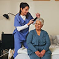 Woman brushing elderly ladies hair