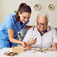 Woman helping old man with puzzle