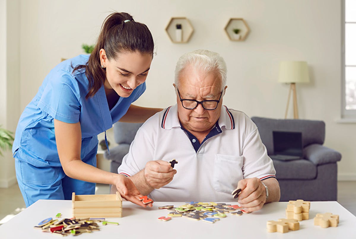 Women helping elderly man with puzzle