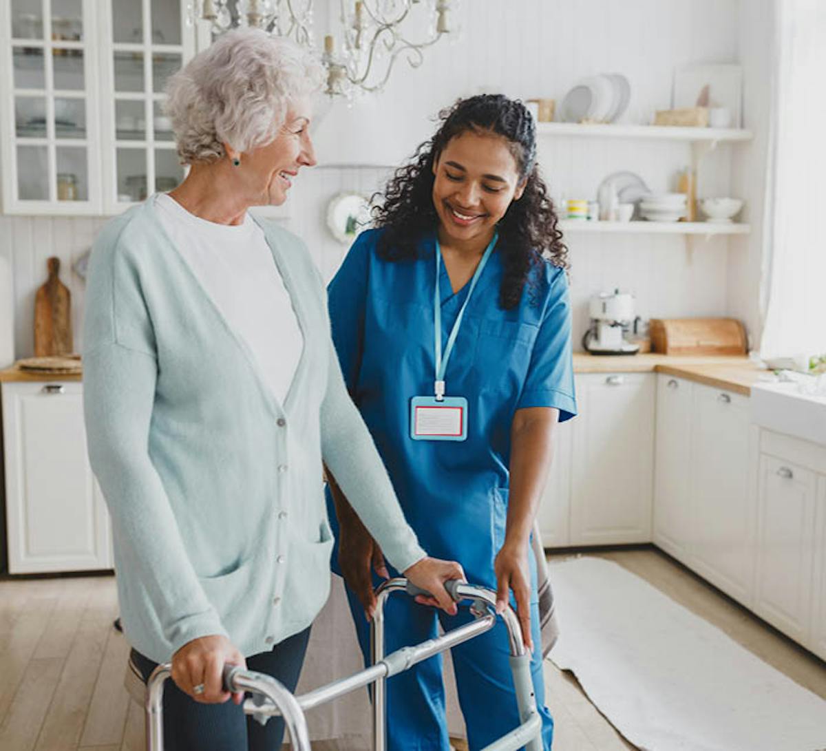 Individual support worker assisting an older woman using a mobility walker in her home
