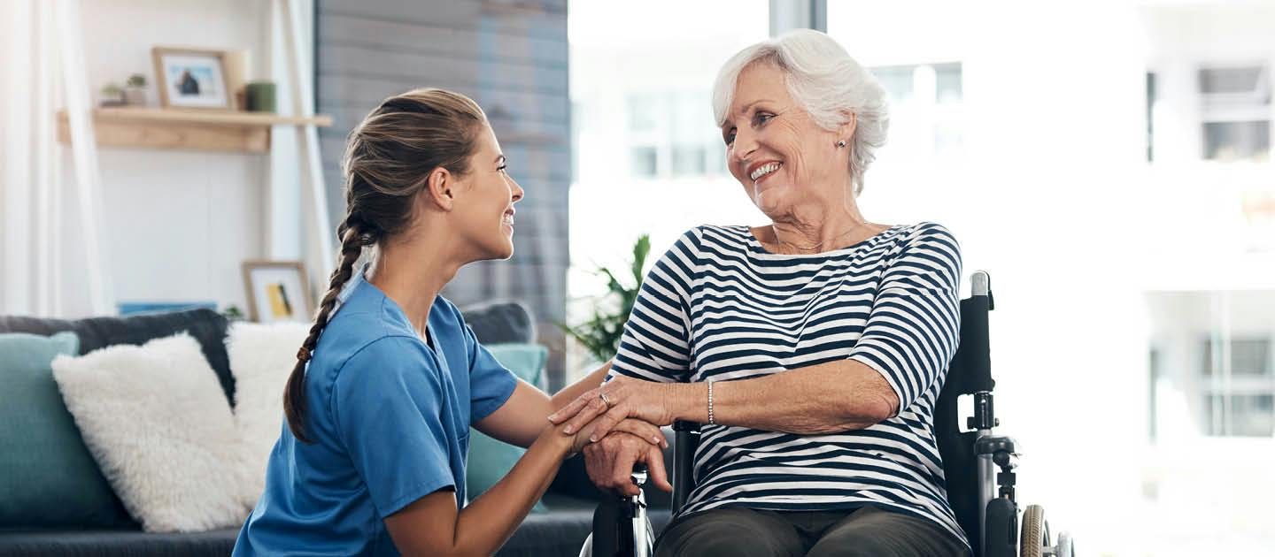 Individual support worker providing care and companionship to an older woman using a wheelchair at home