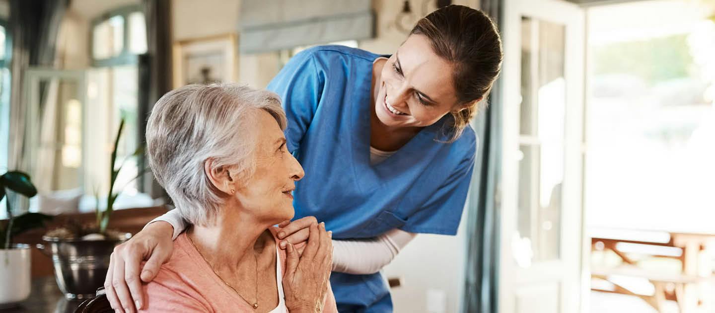 Individual support worker providing companionship and reassurance to an older woman in a home care setting