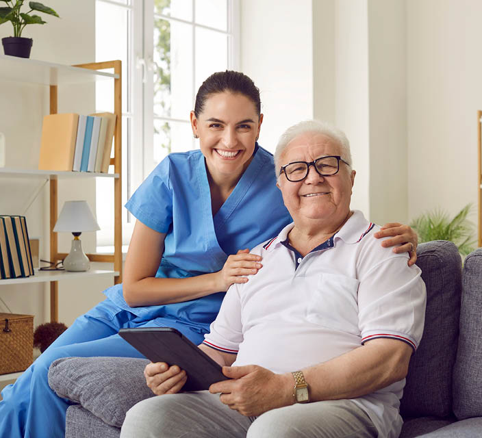 Aged care support worker sitting with an older man in a home care setting.