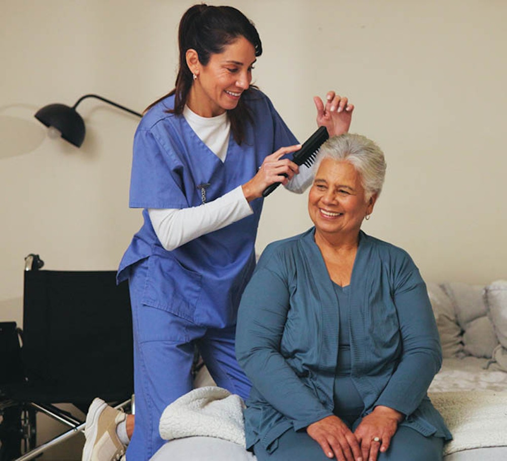 Disability support worker assisting an older woman with personal care in a home setting