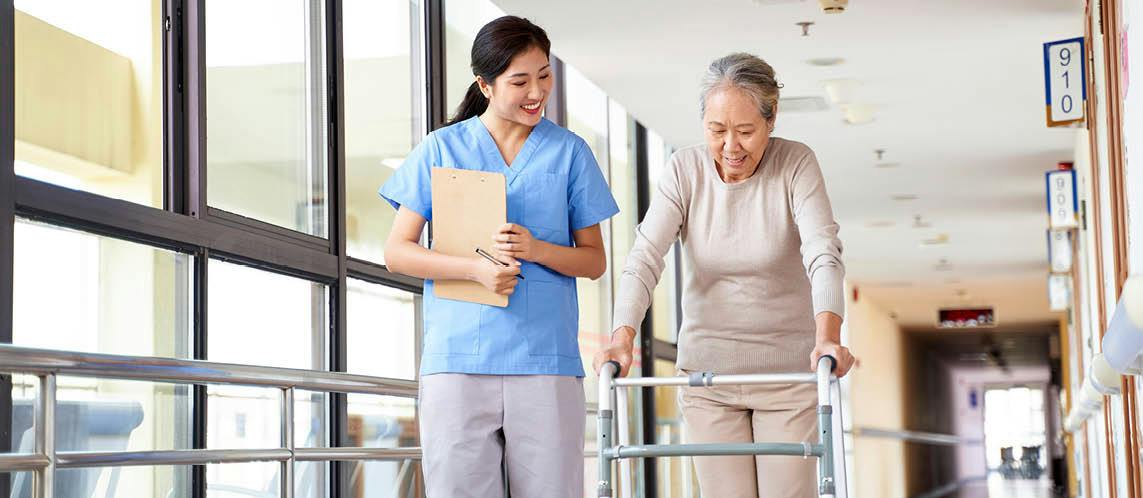 Support worker assisting an older woman to walk safely using a mobility walker