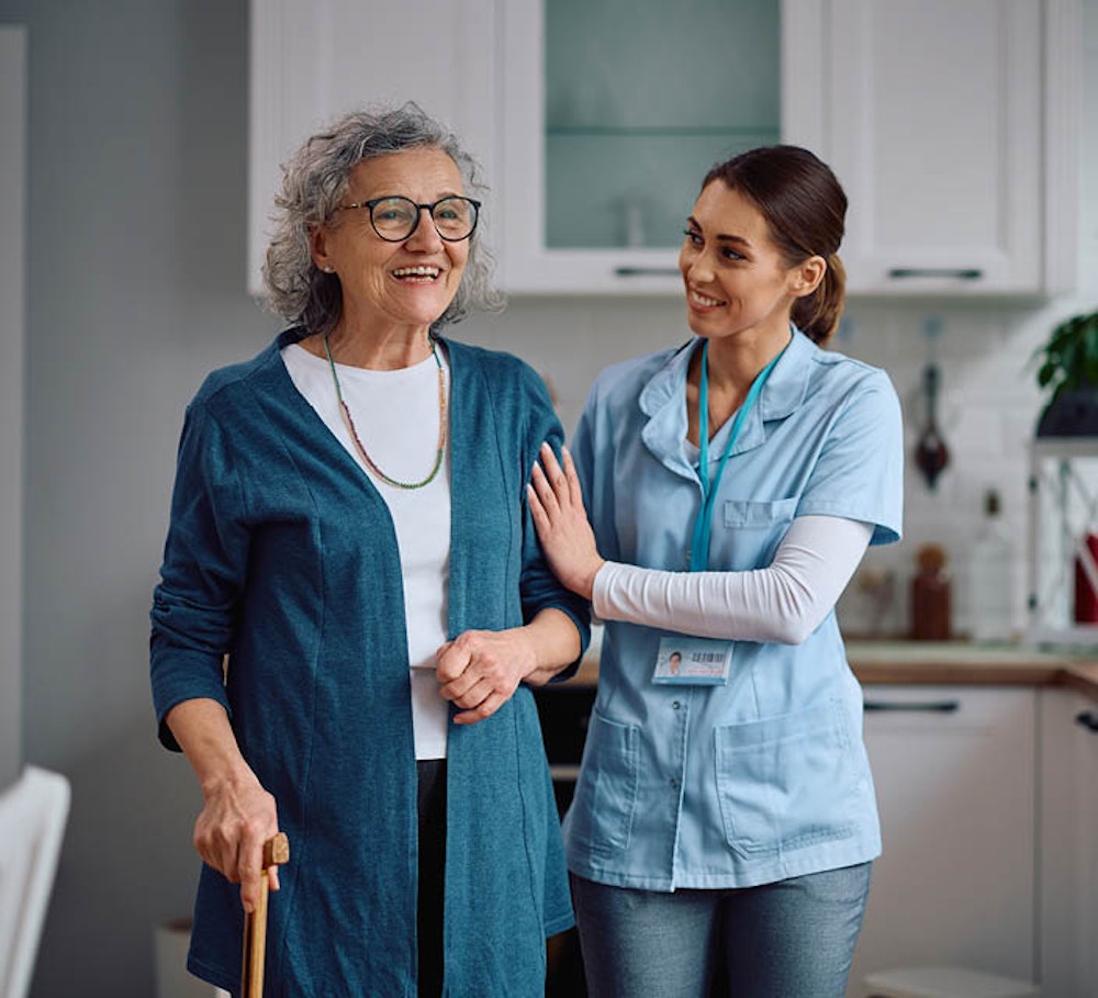 Disability support worker assisting an older woman using a walking aid at home