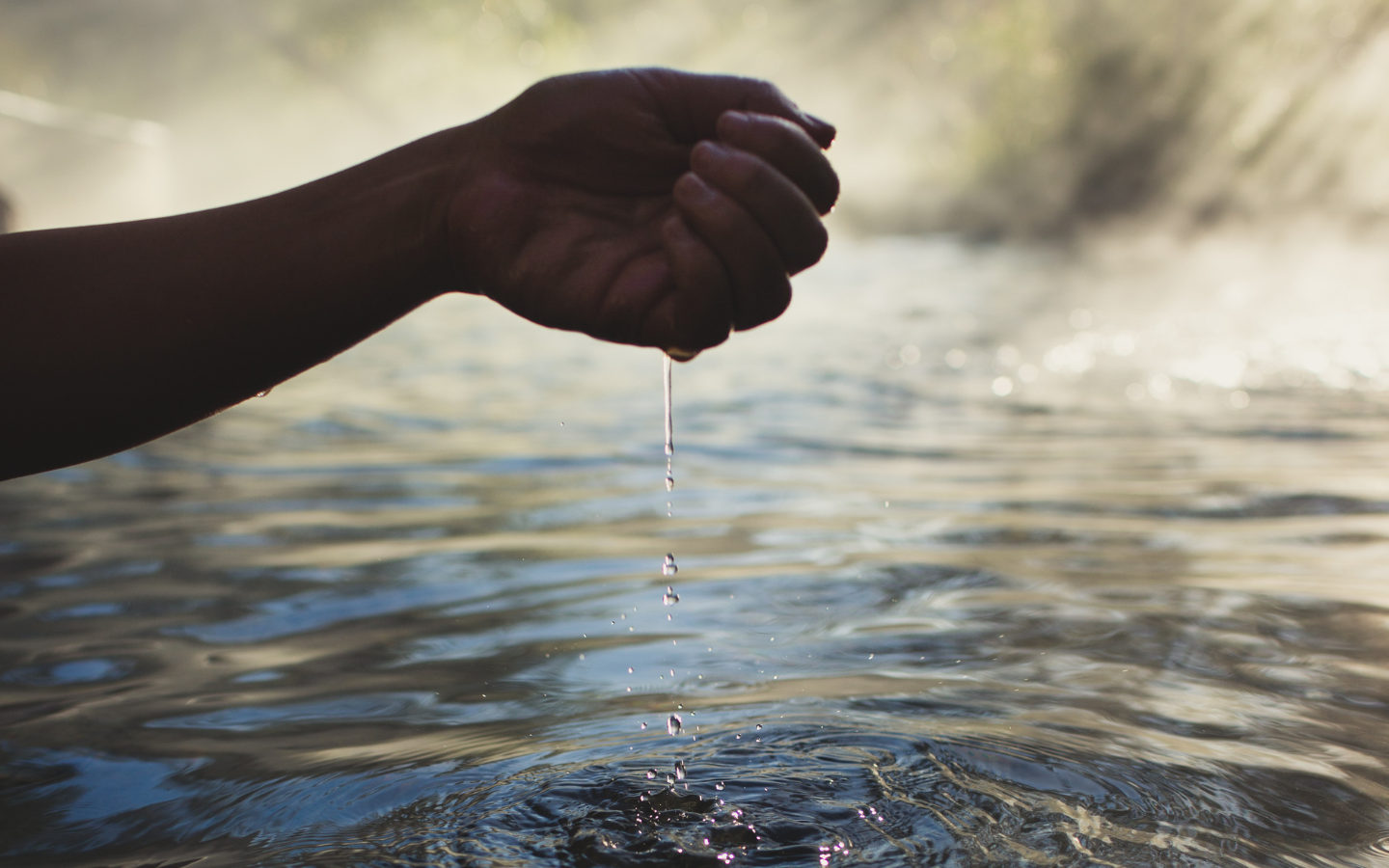 persons hand collecting geothermal hot springs water