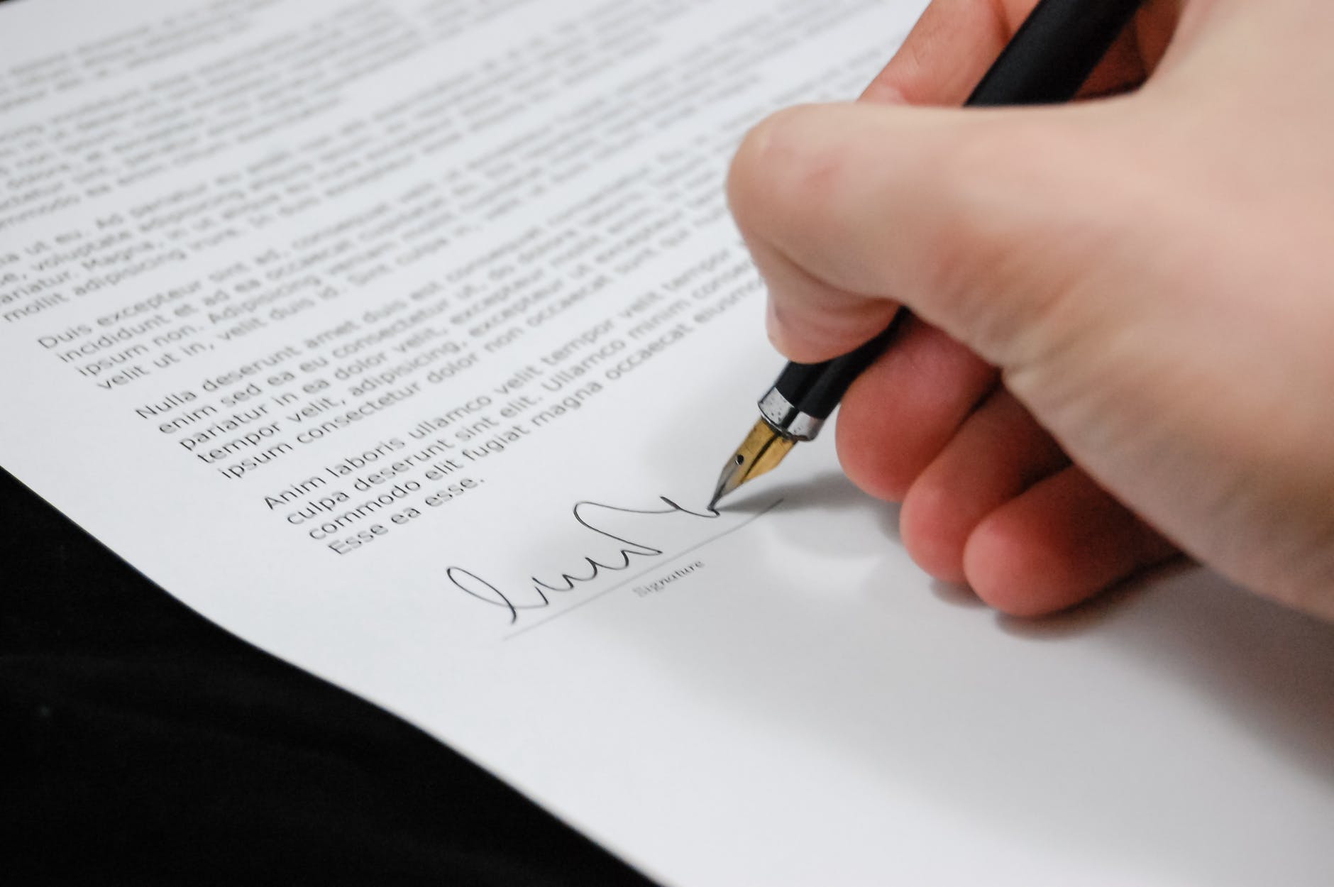main signant un document avec un stylo à plume