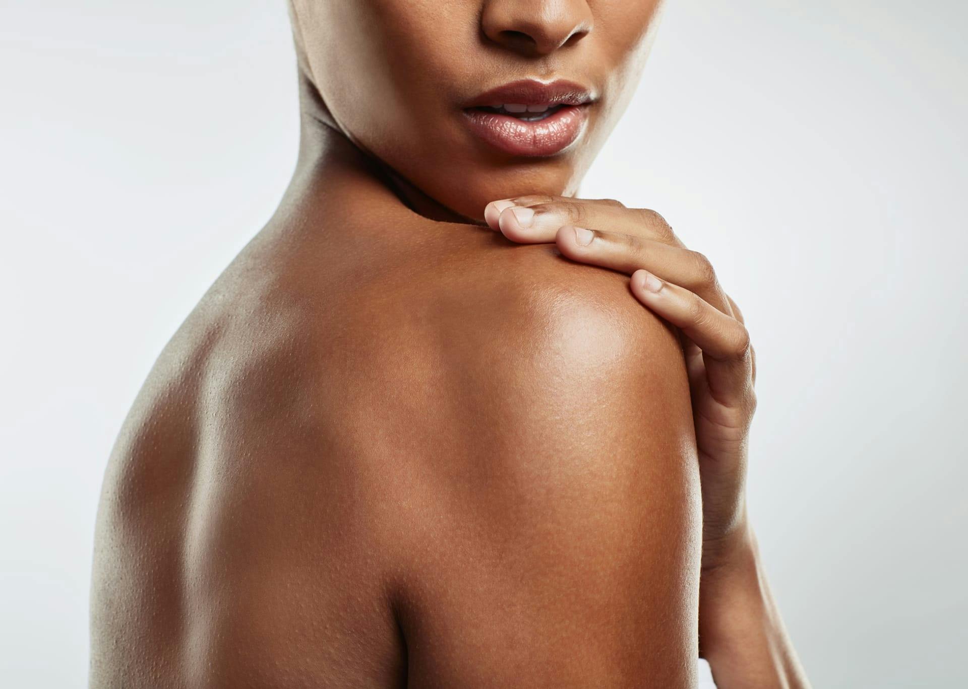 Dark-skinned woman touching her shoulder