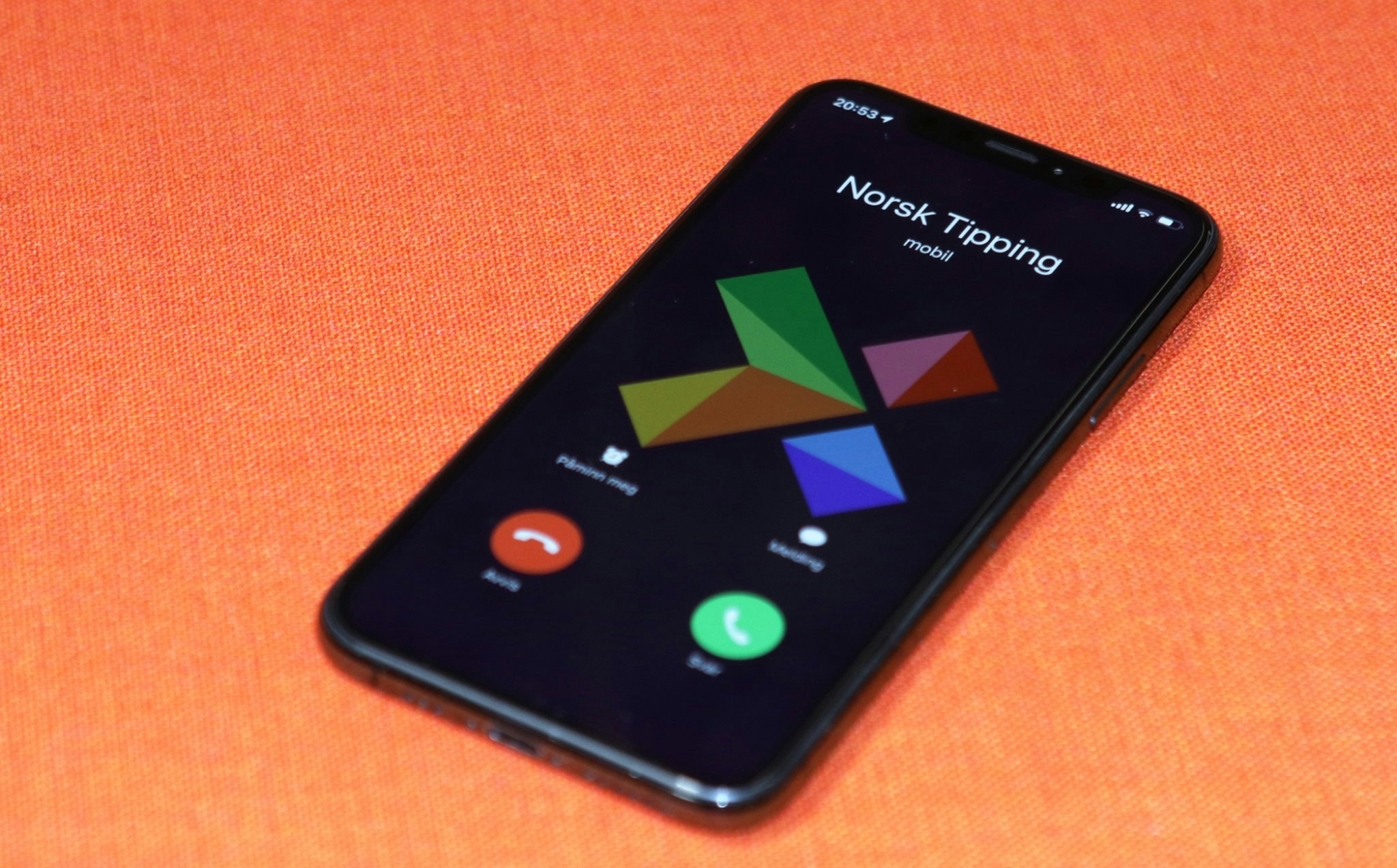 Mobiltelefon på oransje bakgrunn: Norsk Tipping ringer