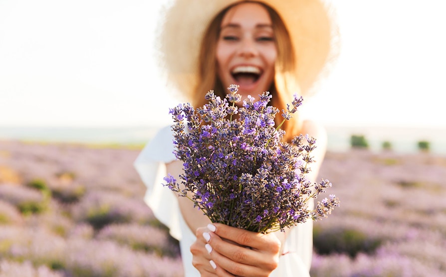 Kvinne som holder lavendel og smiler stort