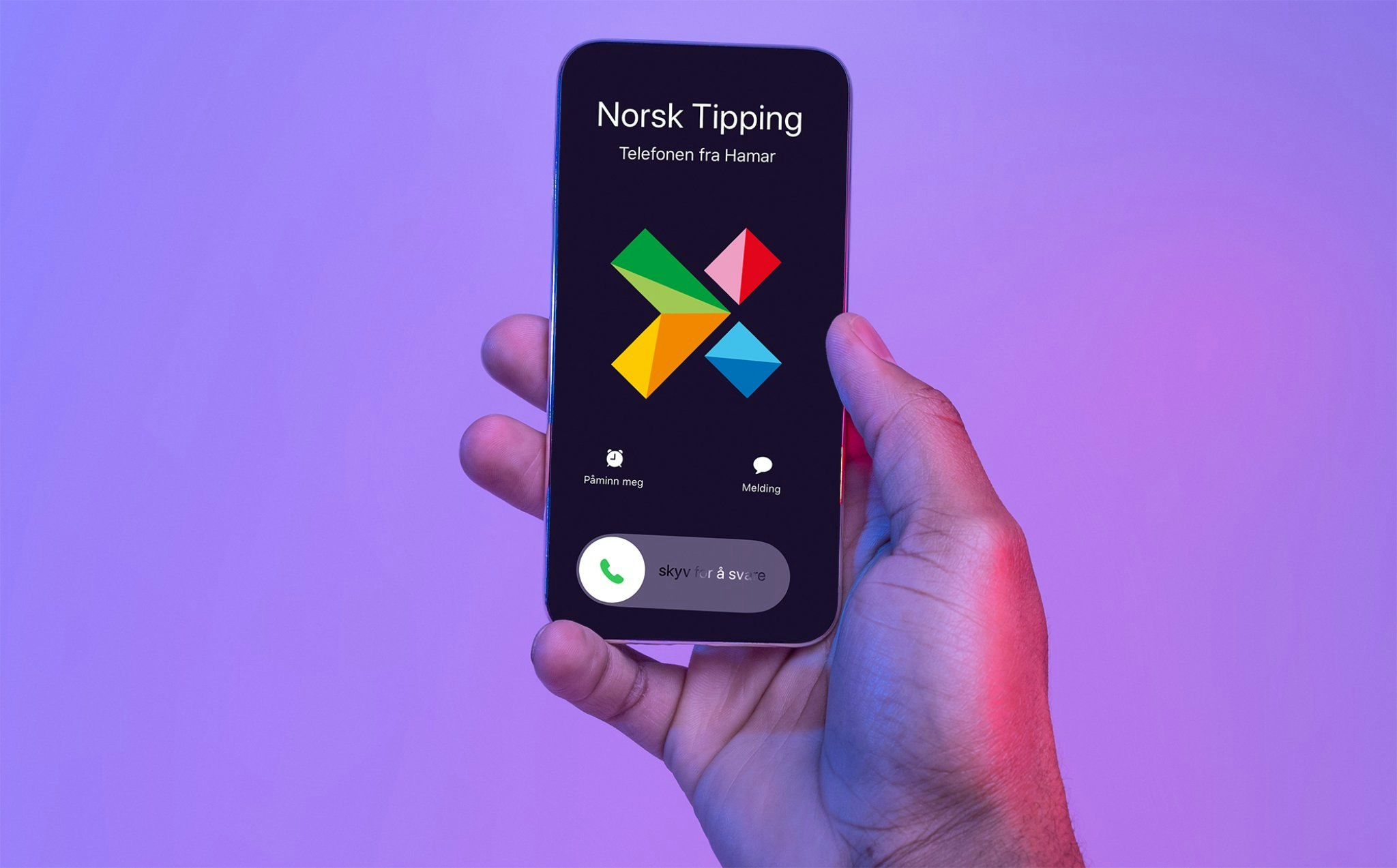Mann holder telefon, det ringer fra Norsk Tipping