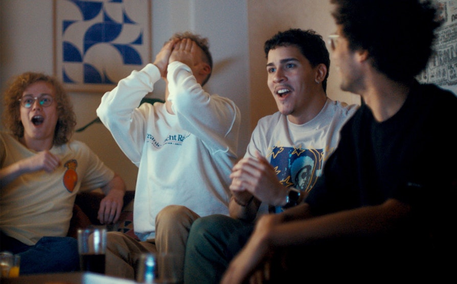 Illustrasjonsfoto av fire menn som reagerer på noe som skjer utenfor skjermen: to er overrasket, en skjuler ansiktet i hendene mens fjerdemann følger leende med