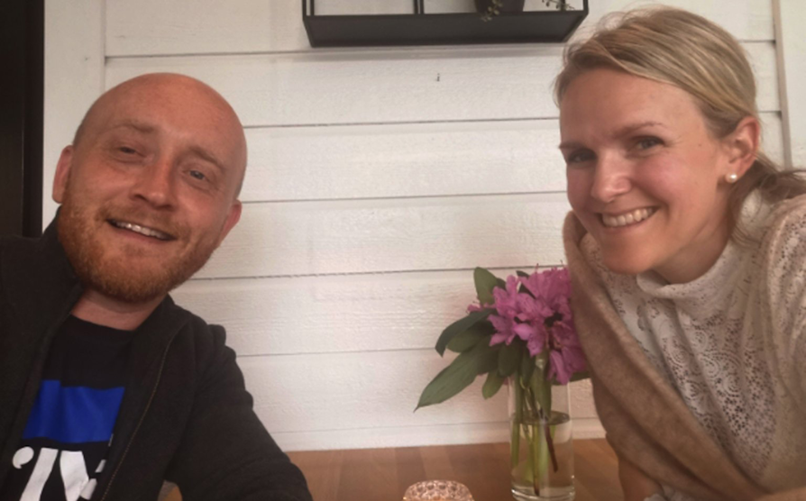 Andelsbank-vinner Simon Engjaberg Øye og kona Gry Sætre Øye lener seg over et restaurantbord og smiler inn i kamera.