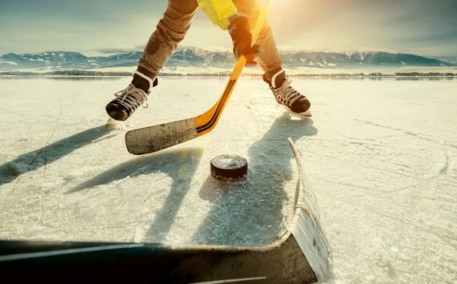 Nærbilde av beina til en hockeyspiller på islagt innsjø