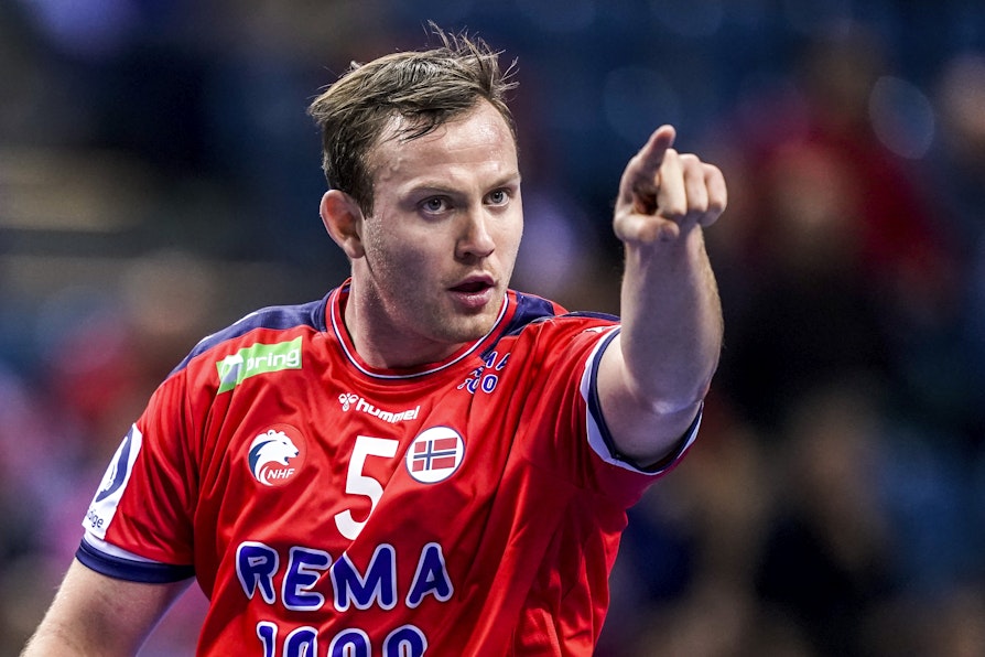 Norsk håndballspiller i rød drakt peker mot deg