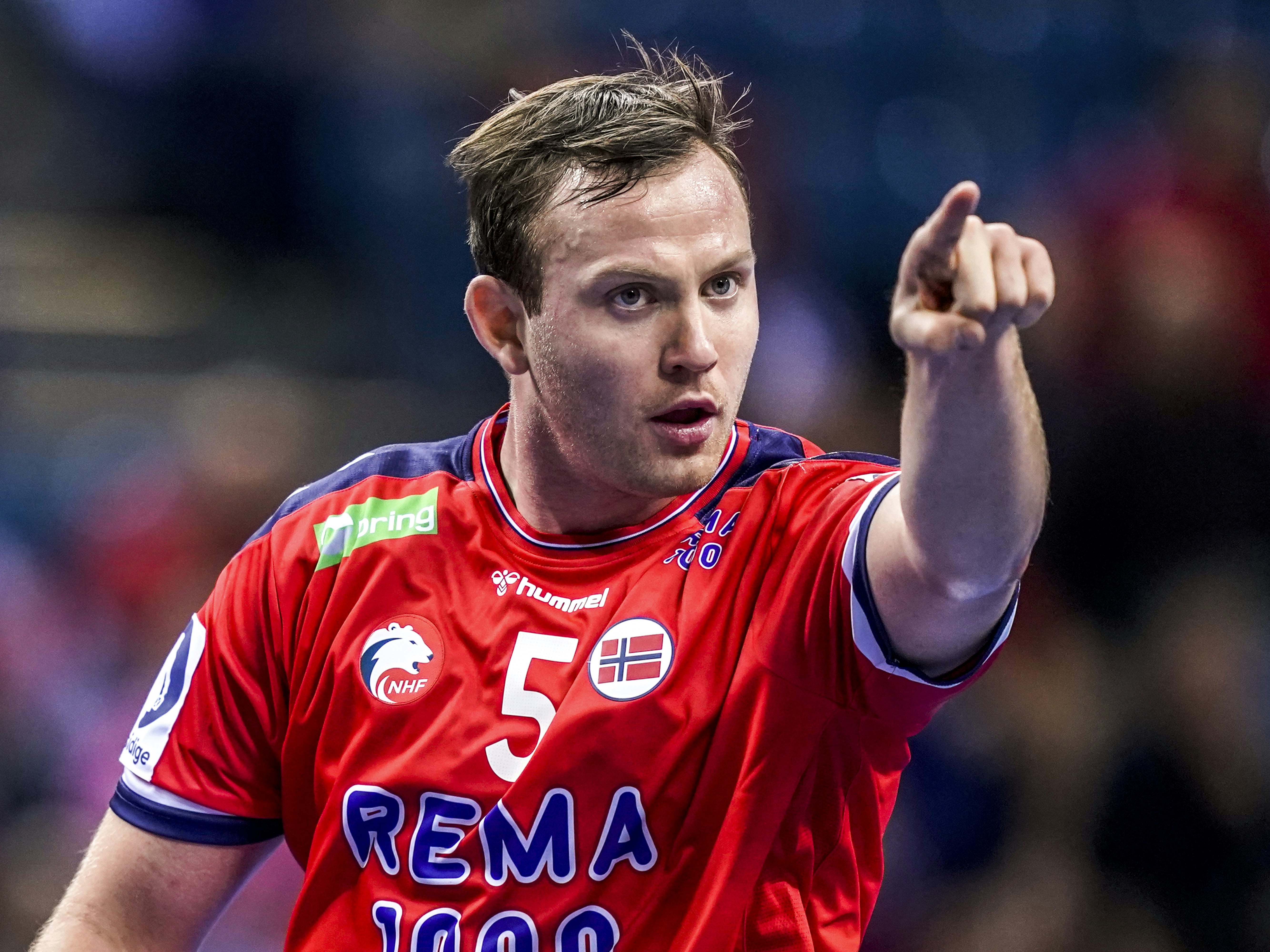 Norsk håndballspiller i rød drakt peker mot deg