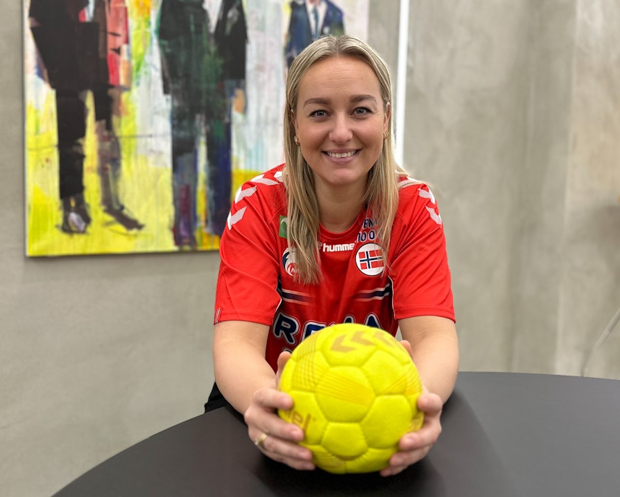 Kvinne i rødt drakt med håndball i hendene