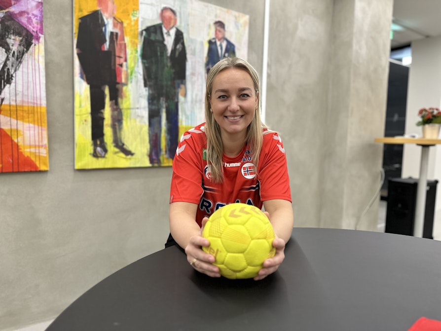 Kvinne i norsk i landslagsdrakt med håndball i hendene