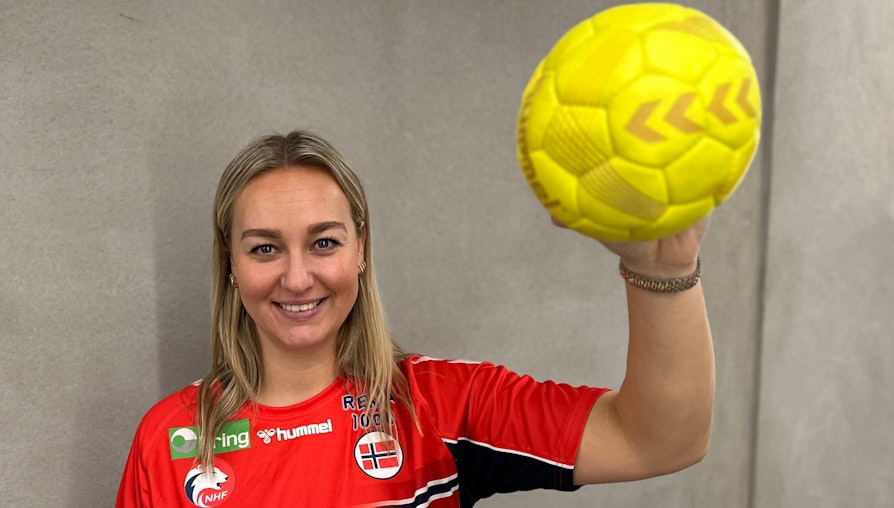 Håndballspiller i rød drakt med ball