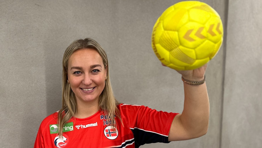 Håndballspiller i rød drakt med ball