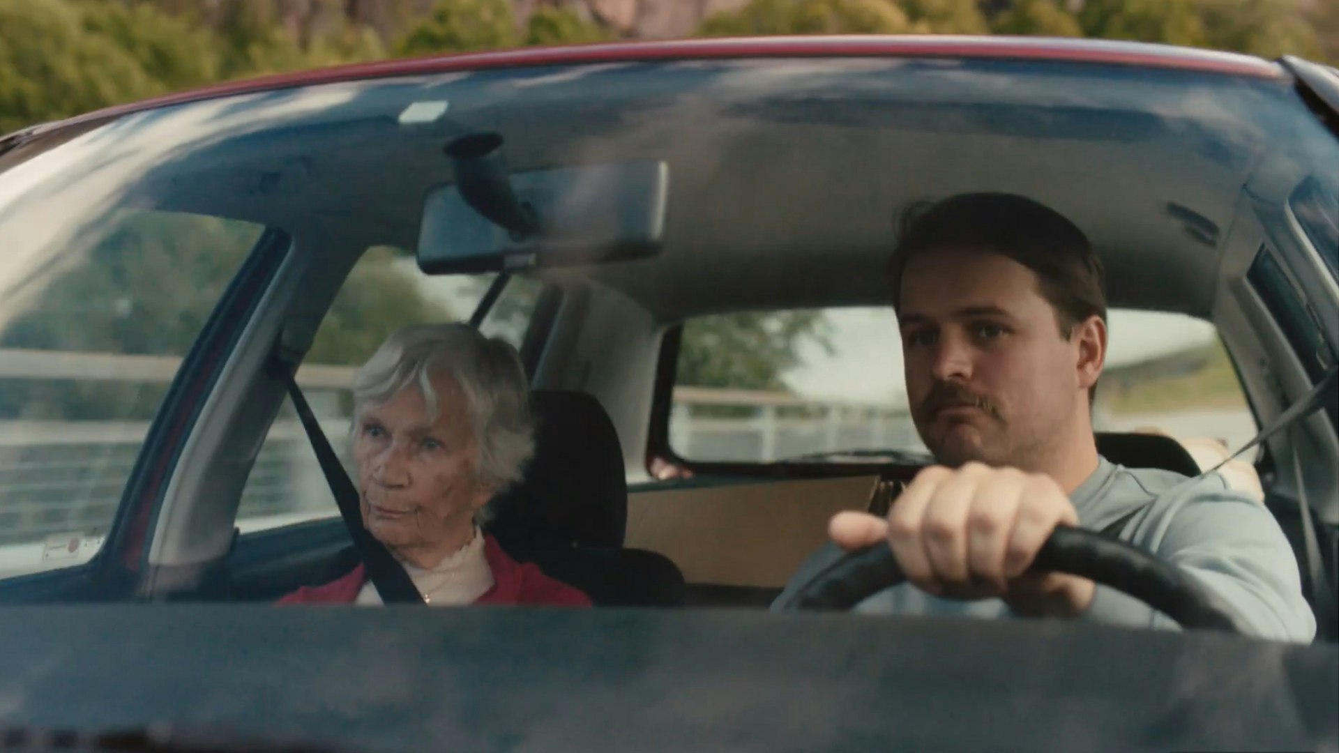 Skjermdump fra Lotto-reklamefilmen «A Room With A View». En gammel kvinne sitter i passasjersetet mens sønnen kjører.