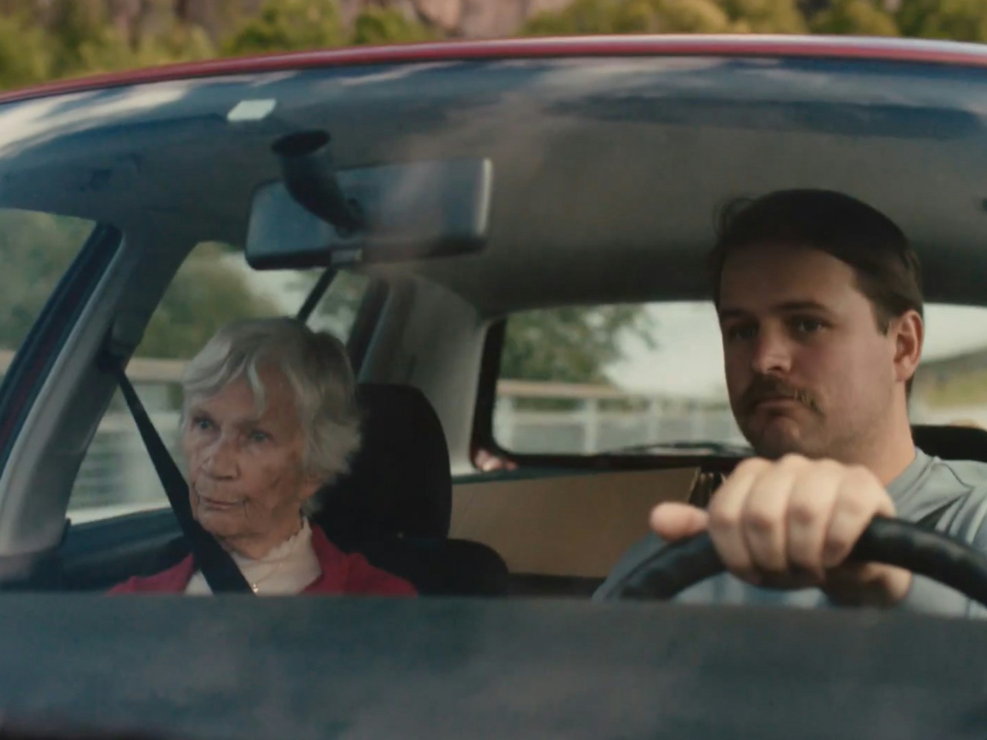 Skjermdump fra Lotto-reklamefilmen «A Room With A View». En gammel kvinne sitter i passasjersetet mens sønnen kjører.