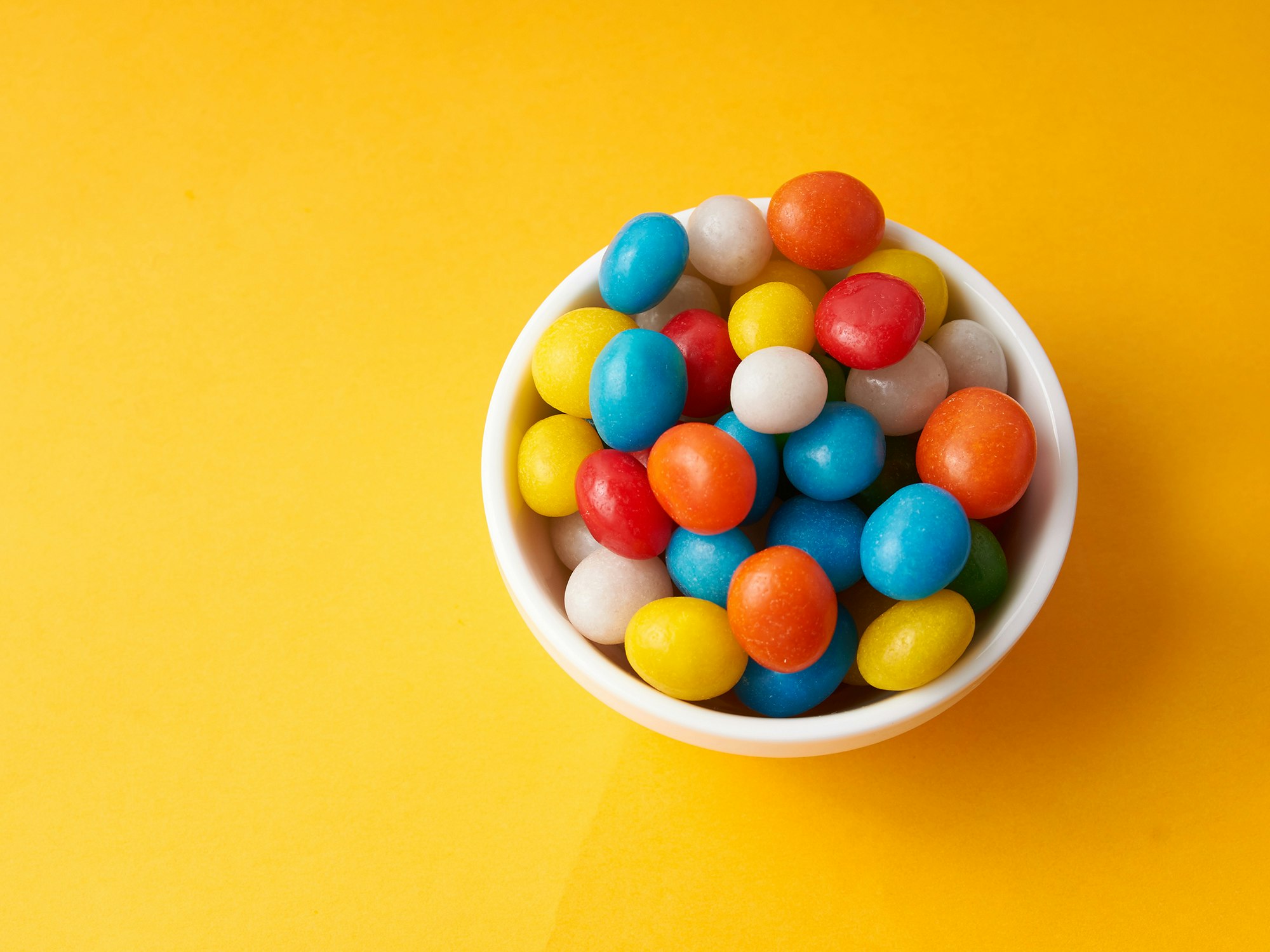 Illustrasjonsfoto av skål med godteri på gul bakgrunn