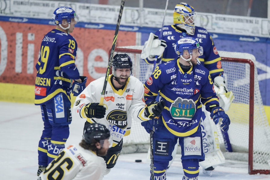 En hockeyspiller i hvit Stavanger drakt jubler etter scoring mot Storhamar i bkå drakter.
