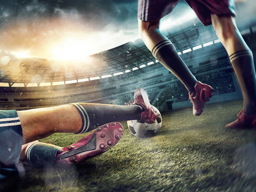 Fotball. Beina på to fotballspillere og en fotball